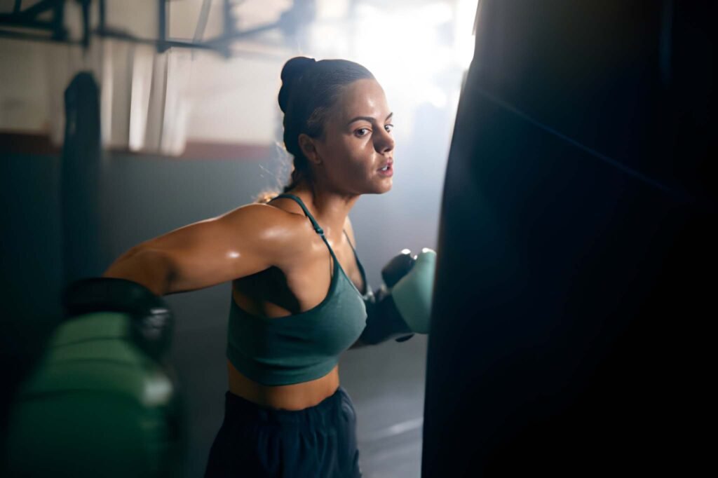 Young woman, with boxing gloves, punching the punching bag